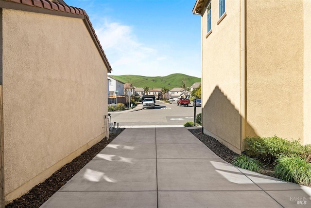 view of side of property with a tile roof, a residential view, a mountain view, and stucco siding