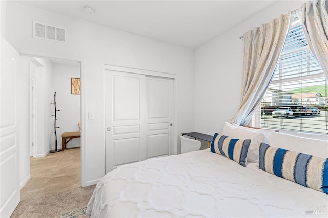 bedroom featuring baseboards, visible vents, a closet, and light colored carpet