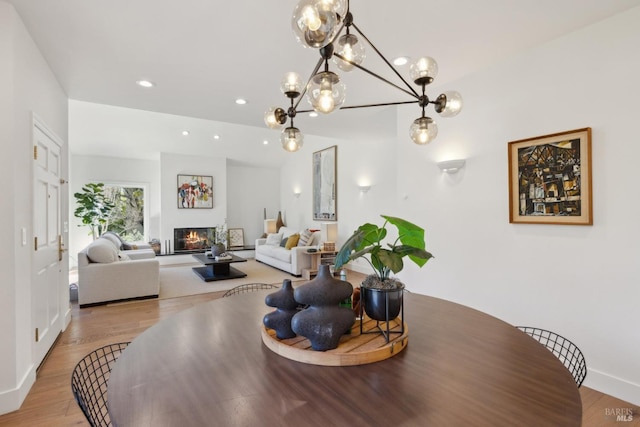 dining area with baseboards, a glass covered fireplace, wood finished floors, and recessed lighting