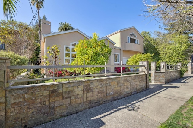 view of front of home with a fenced front yard, a chimney, and stucco siding