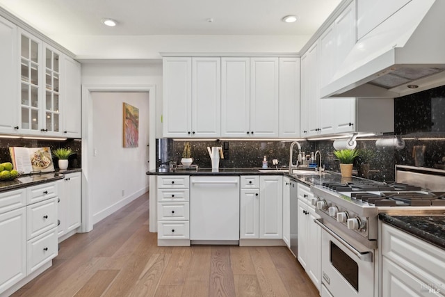 kitchen with high end stainless steel range oven, white dishwasher, light wood-type flooring, under cabinet range hood, and white cabinetry