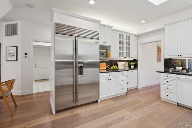 kitchen featuring light wood finished floors, dark countertops, visible vents, and stainless steel built in fridge