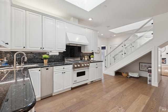 kitchen with high end white range oven, a skylight, a sink, and range hood