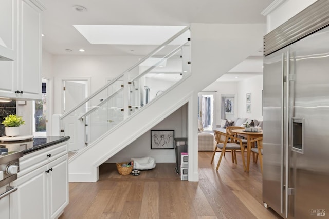 stairs featuring a high ceiling, a skylight, wood finished floors, and recessed lighting