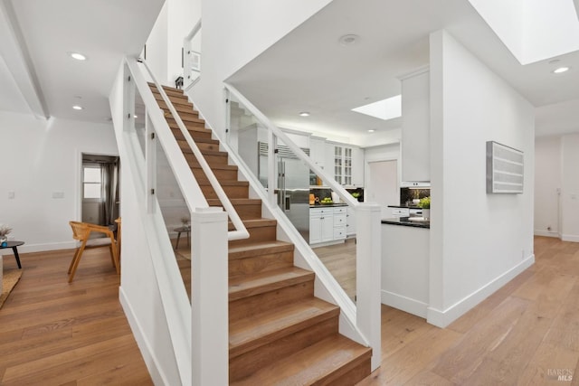 staircase featuring a skylight, hardwood / wood-style flooring, and recessed lighting