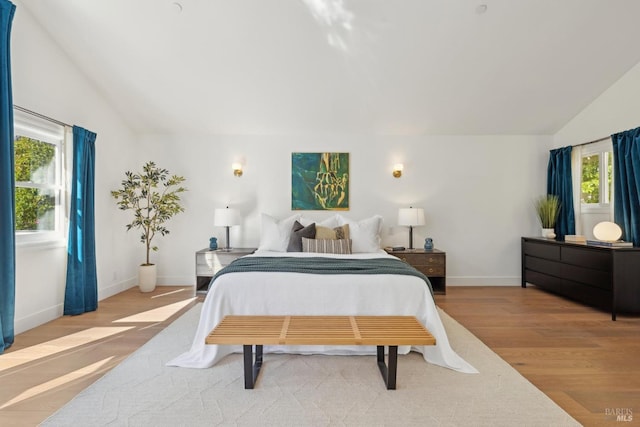 bedroom with vaulted ceiling, baseboards, and wood finished floors