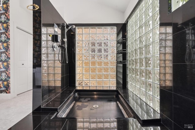 full bath featuring lofted ceiling and tiled shower