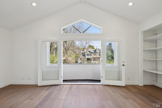 entryway featuring vaulted ceiling, built in shelves, wood finished floors, and baseboards