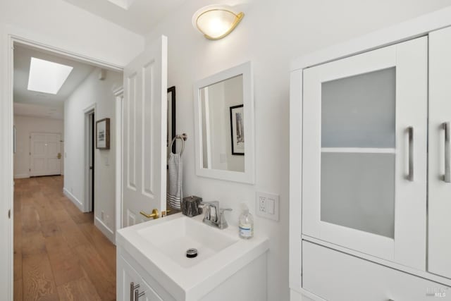 bathroom featuring a skylight, wood finished floors, and vanity