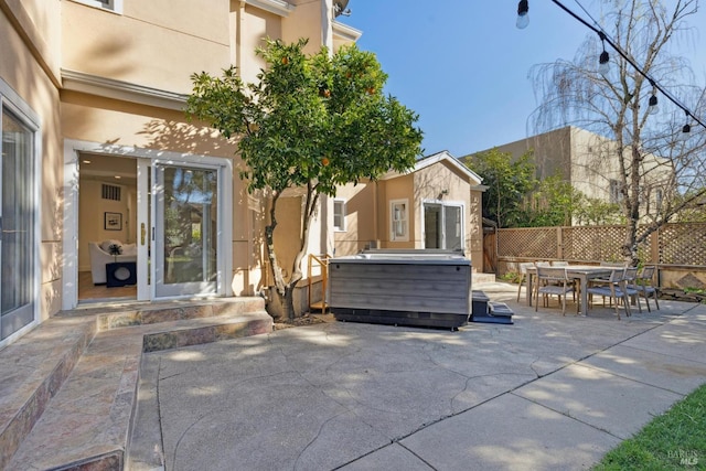 view of patio featuring a hot tub, fence, and outdoor dining space