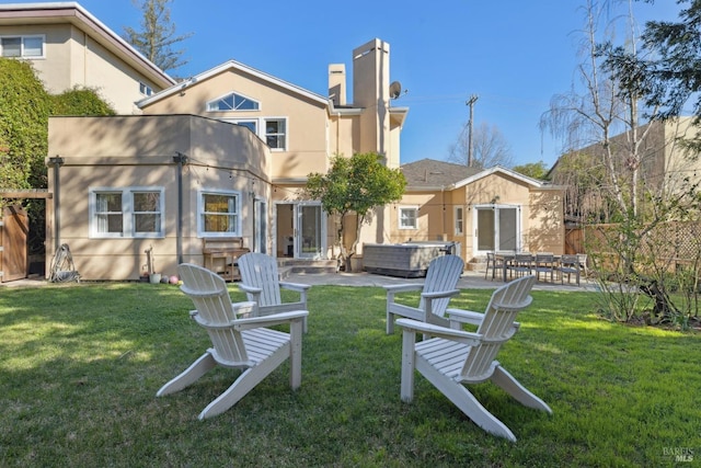 rear view of property featuring a yard, a patio, and stucco siding