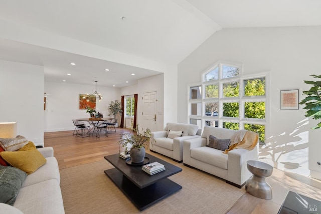 living area with a chandelier, high vaulted ceiling, light wood-style flooring, and recessed lighting