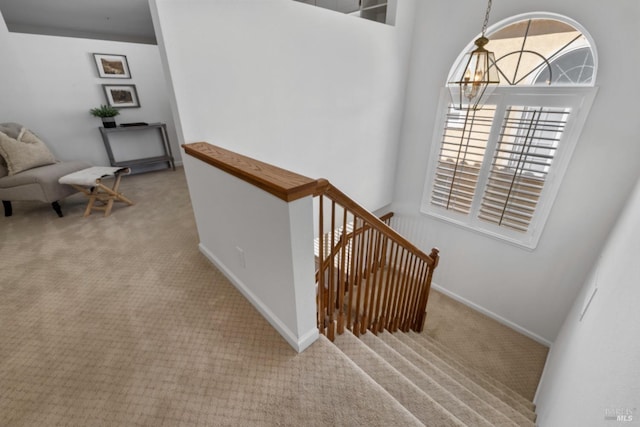 stairs featuring carpet flooring, baseboards, and an inviting chandelier