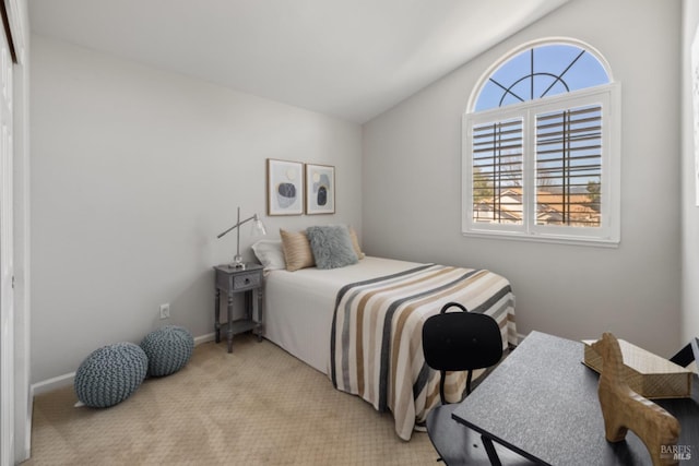 bedroom with vaulted ceiling, baseboards, and light colored carpet