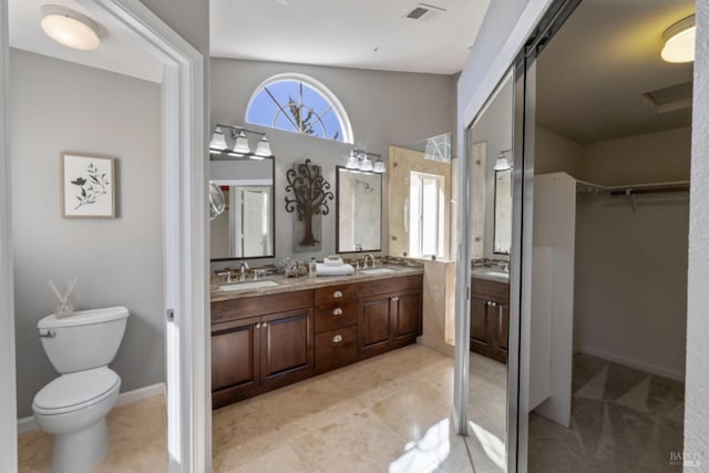 bathroom with double vanity, a sink, visible vents, and a walk in closet