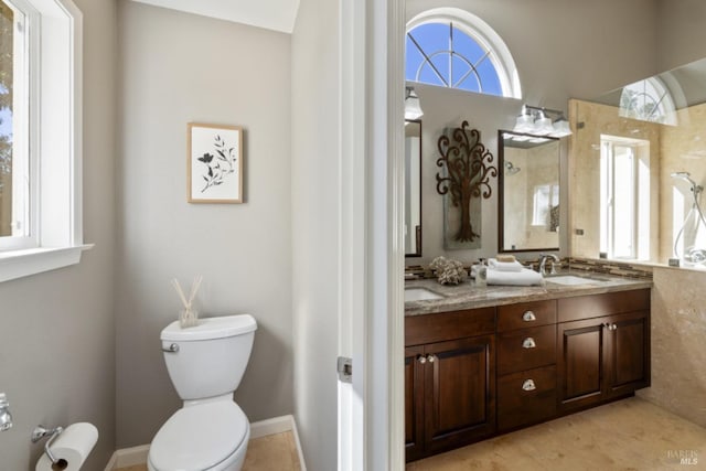 bathroom featuring toilet, double vanity, and a sink