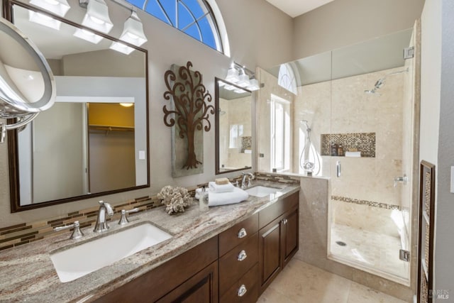 full bath featuring a stall shower, double vanity, a sink, and tile patterned floors