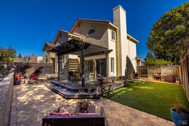 back of property featuring a pergola, a chimney, a deck, a fenced backyard, and a yard