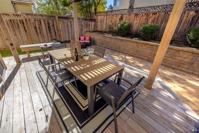 wooden terrace featuring outdoor dining area and a fenced backyard