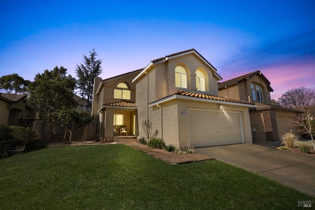 view of front facade with concrete driveway, stucco siding, a tile roof, fence, and a front yard