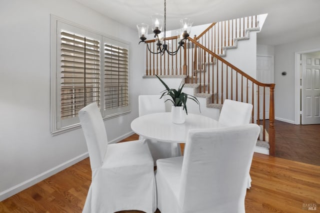 dining space featuring stairway, baseboards, wood finished floors, and a chandelier