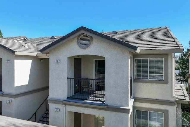 exterior space with a tile roof and stucco siding