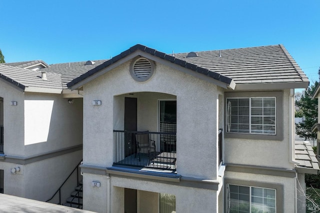 exterior space with stucco siding and a tiled roof