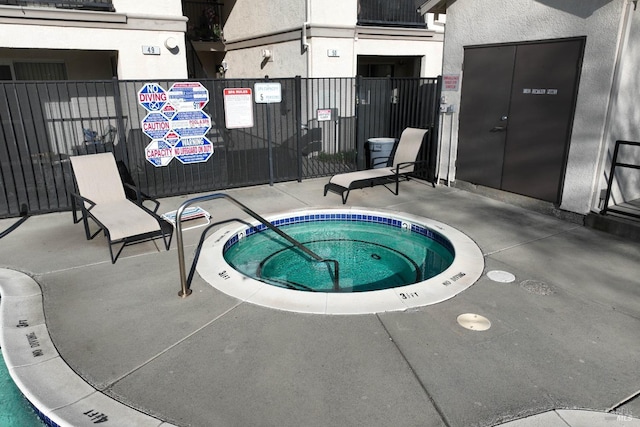 view of swimming pool featuring a community hot tub and fence