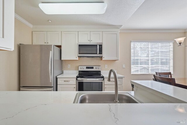 kitchen featuring a sink, white cabinets, appliances with stainless steel finishes, and ornamental molding