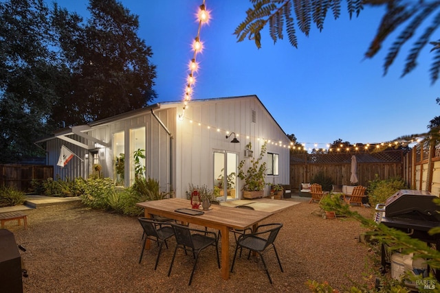 rear view of house featuring board and batten siding, a patio area, and fence