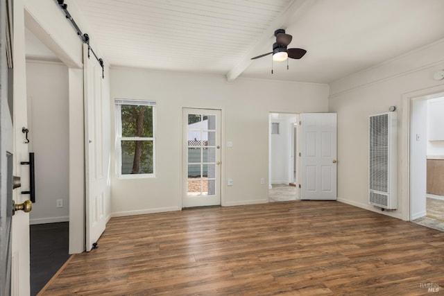 interior space with wood finished floors, a heating unit, beamed ceiling, and a barn door