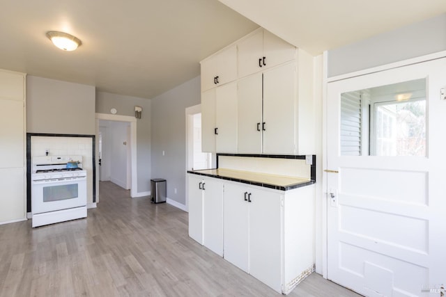 kitchen featuring light wood finished floors, backsplash, white cabinetry, and white range with gas stovetop