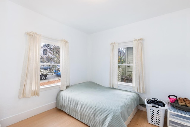 bedroom with multiple windows, baseboards, and wood finished floors