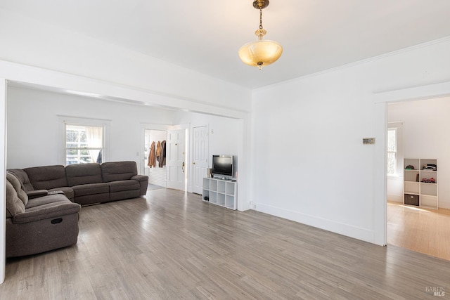 living room featuring crown molding, baseboards, and wood finished floors