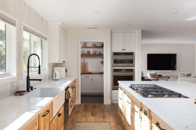 kitchen with visible vents, appliances with stainless steel finishes, light wood-style floors, white cabinets, and a sink