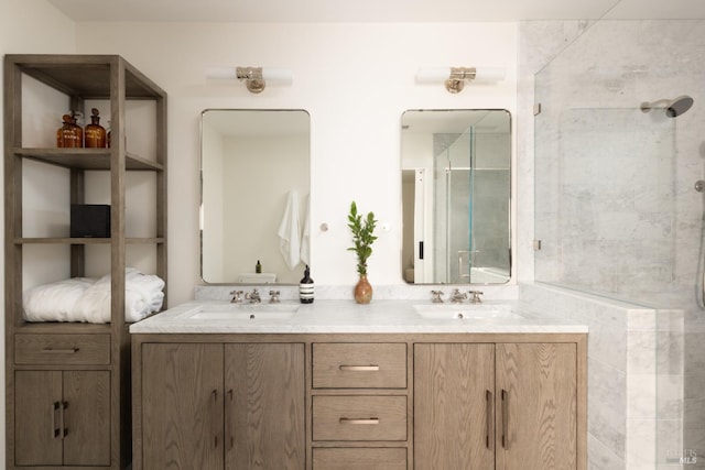 bathroom with tiled shower, a sink, and double vanity