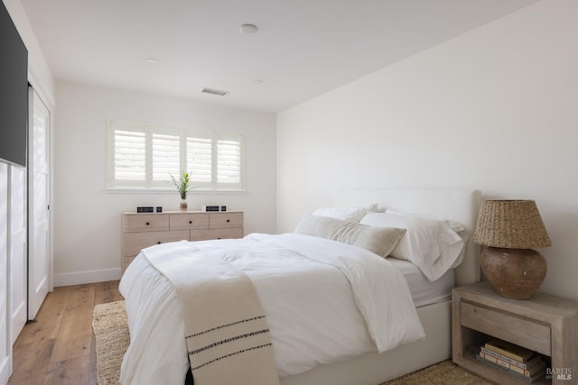 bedroom featuring visible vents, light wood-style flooring, and baseboards