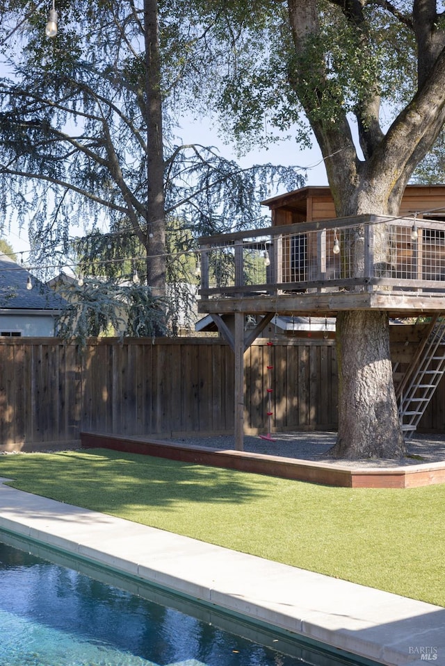 view of swimming pool featuring a wooden deck, a lawn, fence, and a fenced in pool