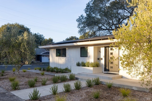 view of front of home with roof mounted solar panels and board and batten siding