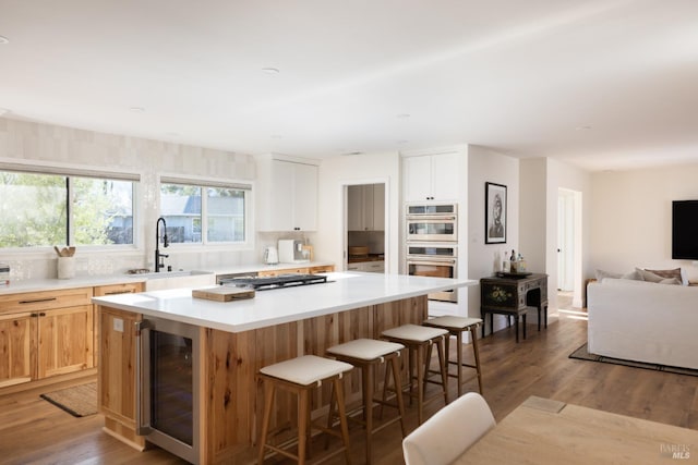 kitchen featuring beverage cooler, stainless steel appliances, a kitchen island, a sink, and a kitchen breakfast bar