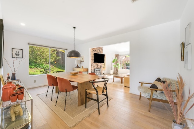 dining room featuring light wood-style flooring, a fireplace, baseboards, and recessed lighting