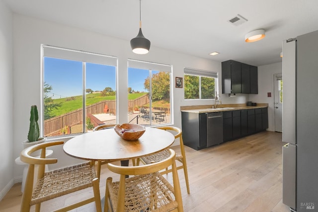 kitchen with stainless steel appliances, a sink, visible vents, light countertops, and dark cabinetry