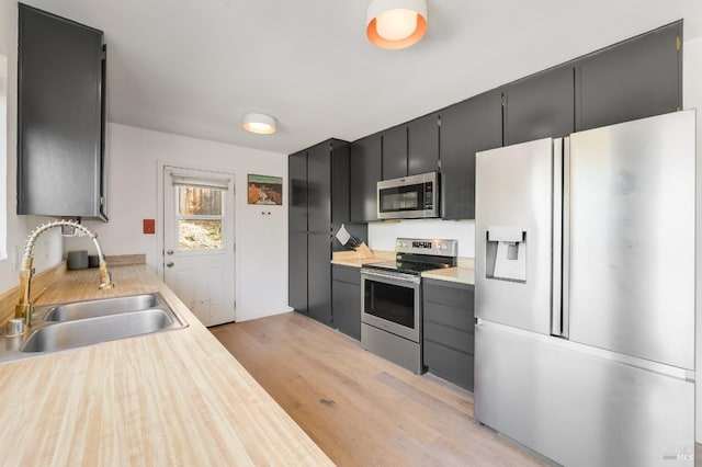 kitchen featuring light wood-type flooring, stainless steel appliances, a sink, and light countertops