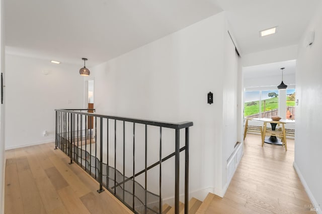 hall featuring wood finished floors, an upstairs landing, and baseboards