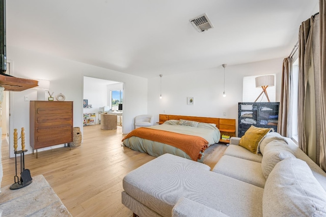 bedroom featuring light wood-style flooring, visible vents, and ensuite bathroom