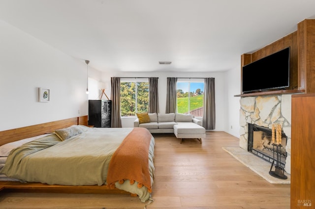 bedroom with light wood-style floors, visible vents, and a fireplace