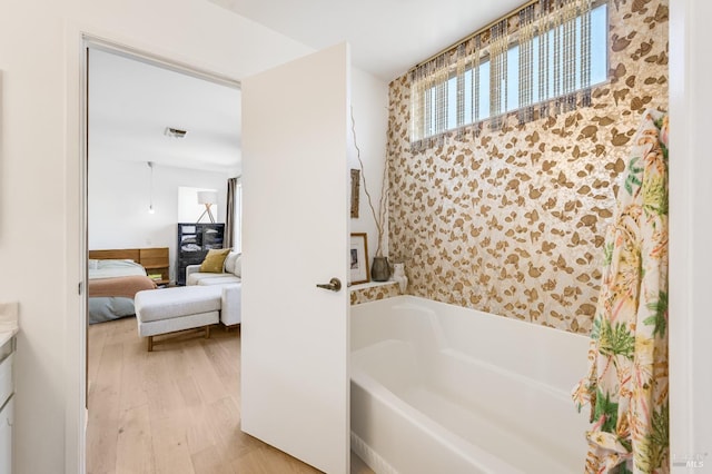 full bath featuring a washtub, connected bathroom, visible vents, and wood finished floors