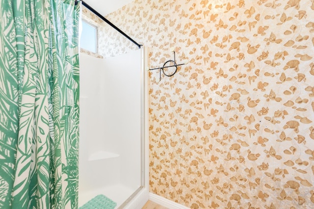 full bathroom featuring a shower, baseboards, and wallpapered walls