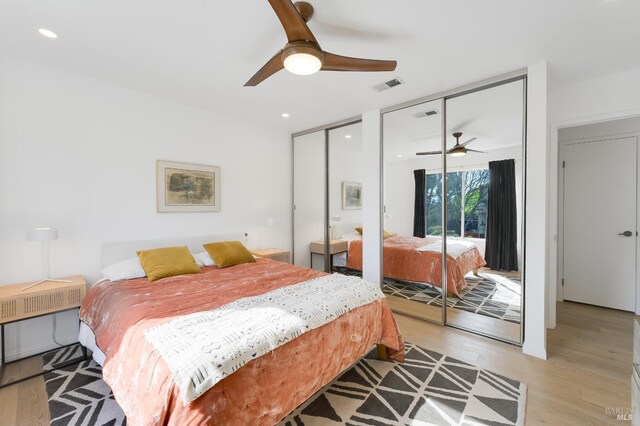 bedroom featuring light wood-type flooring, visible vents, two closets, and recessed lighting