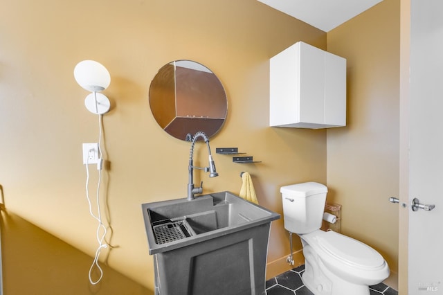 half bathroom featuring baseboards, a sink, toilet, and tile patterned floors